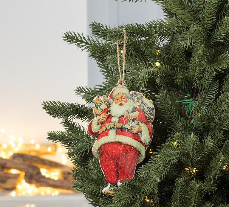 Decorative Santa Claus metal ornament hanging on a Christmas tree with a warm glow in the background.