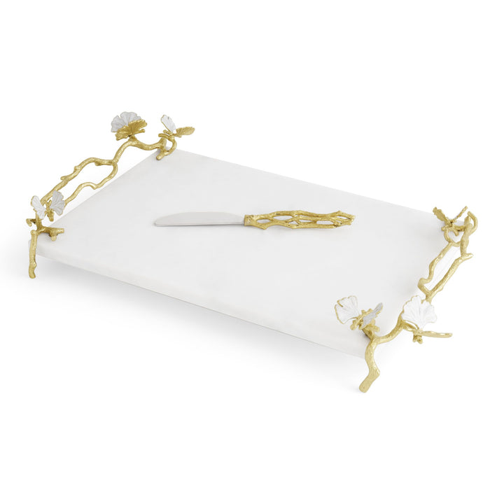 Angled view of Michael Aram Butterfly Ginkgo Gold Cheese Board with Spreader showing white marble, sculptural gold branch handles and legs with white enamel butterflies 