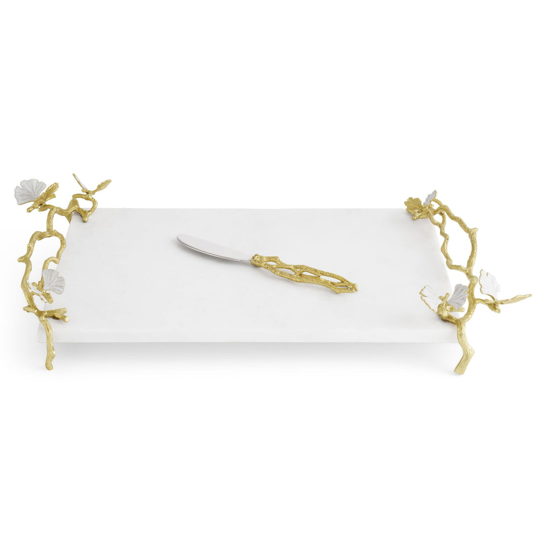 Michael Aram Butterfly Ginkgo Gold Cheese Board with coordinating spreader displayed on the white marble board with sculptural gold butterfly handles