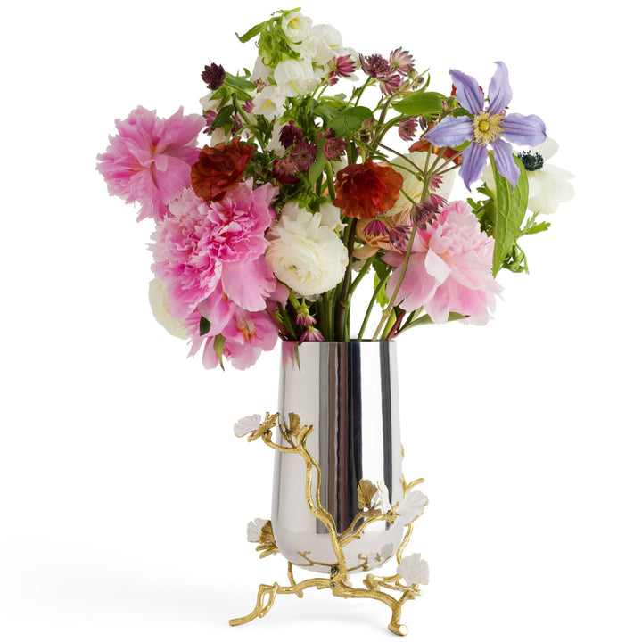Michael Aram Butterfly Ginkgo medium vase filled with flowers, showing its reflective silver-tone body, sculpted gold branches and dimensional white butterfly-like leaves as a decorative floral centrepiece.
