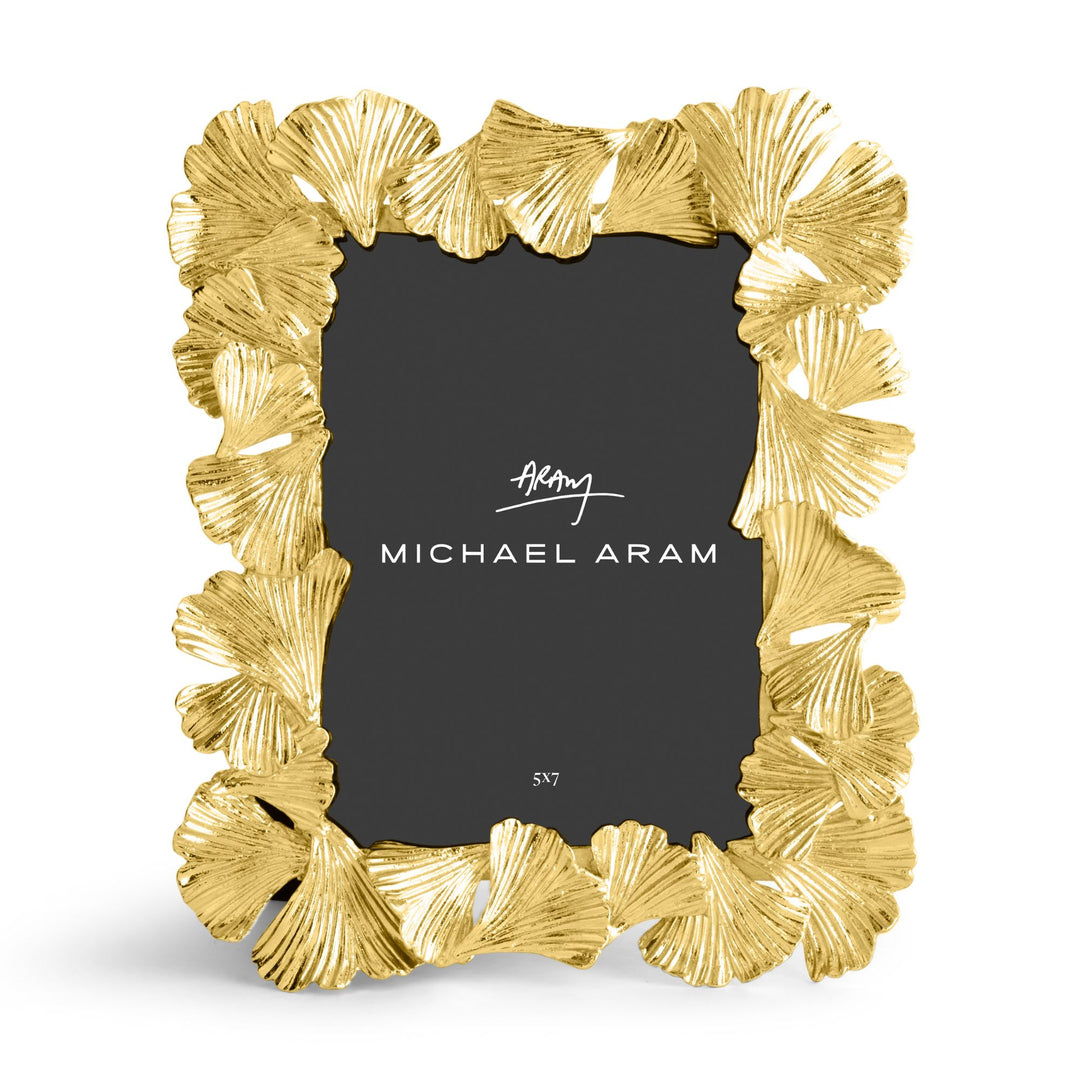 Michael Aram 5x7' gold picture frame with a textured, ginkgo leaf scalloped border, shown with a black insert displaying the Michael Aram logo, displayed verticallly