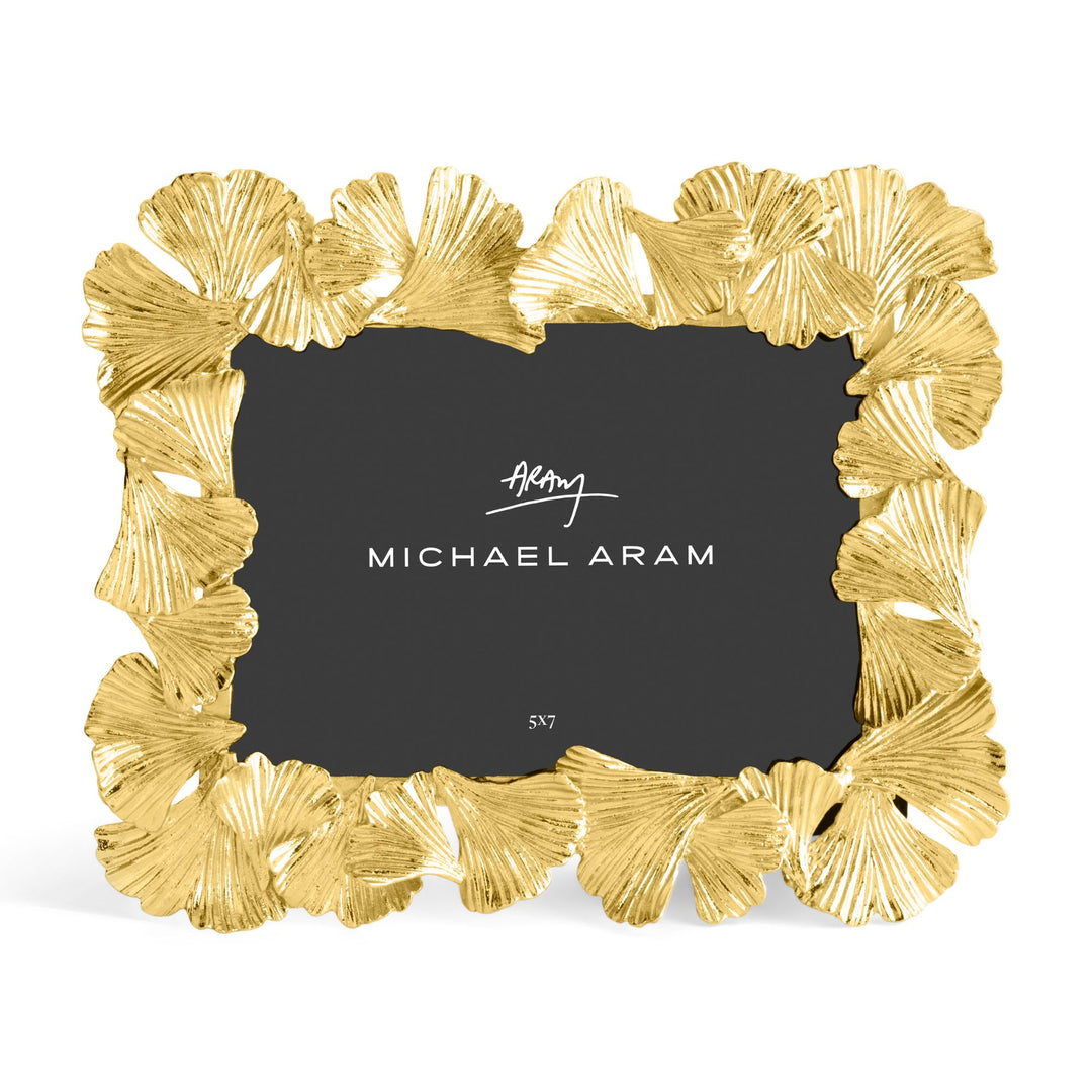 Michael Aram 5x7" gold picture frame with a textured, ginkgo leaf scalloped border, shown with a black insert displaying the Michael Aram logo and sitting horizontally 
