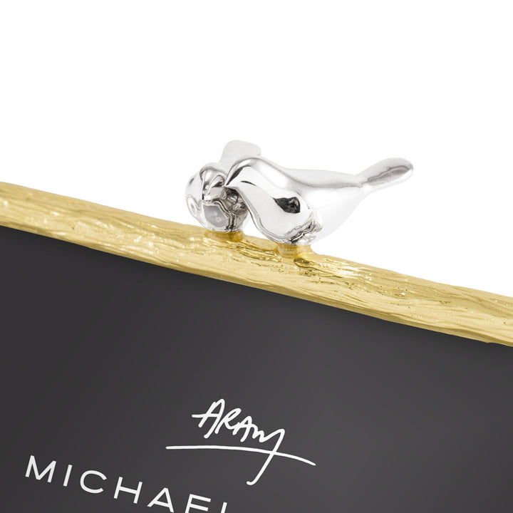 Close-up of two sculpted silver-tone polished lovebirds nestled together atop the textured gold-tone Michael Aram Lovebirds 4x6 picture frame