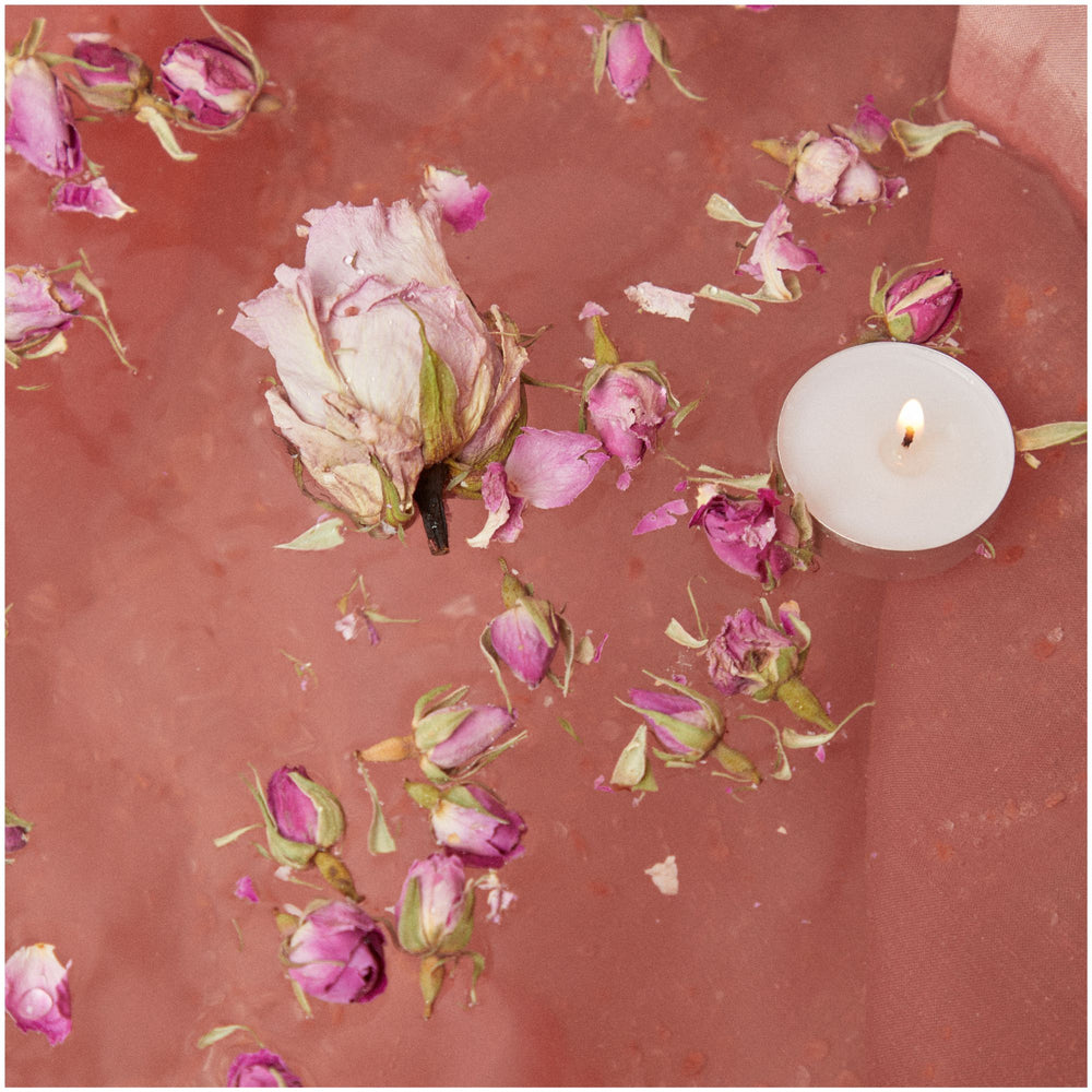 SELV Rituel Quartz Immersive Bath Ritual  shown with contents of kit: floating flowers, rose buds and candle in bath water
