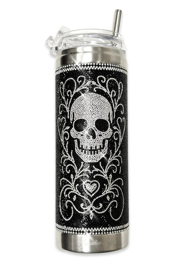 A black and silver Jacqueline Kent insulated travel tumbler with a clear lid and straw, decorated with  rhinestones with a skull and ornate scrollwork pattern.