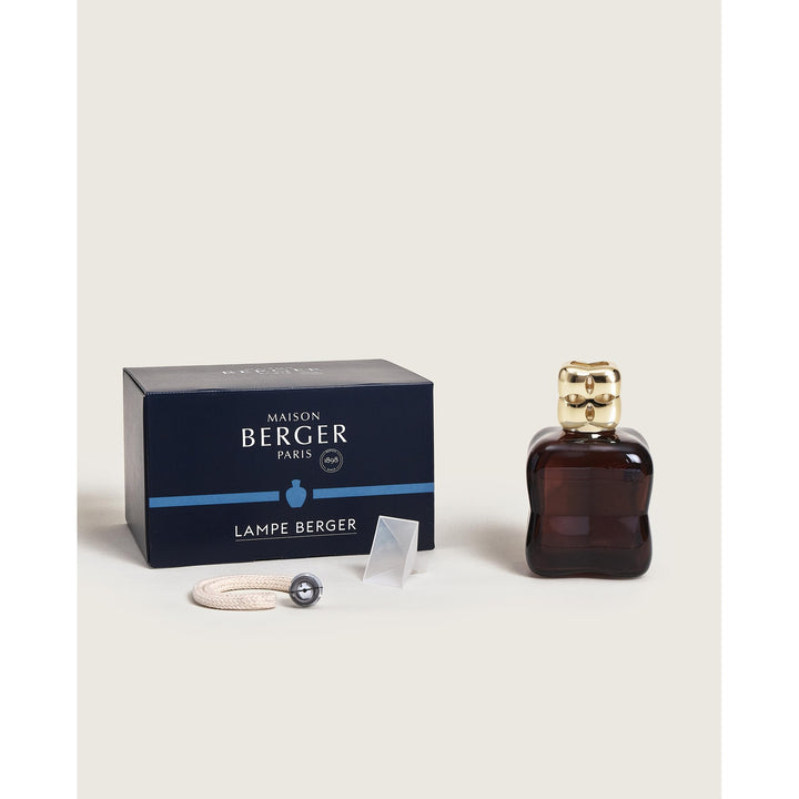 Maison Berger Paris Lampe Berger Cosy Plum box contents featuring a dark plum glass bottle with a gold diffuser cap, its navy blue gift packaging box, wick burner and funnel.