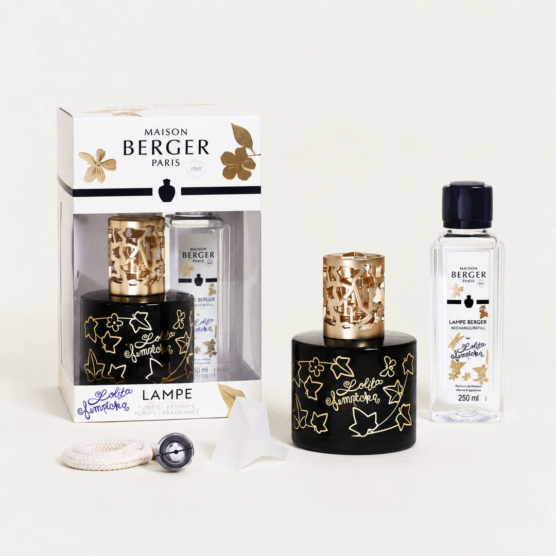 Lampe Berger Lolita Lempicka home fragrance lamp in black glass with gold ivy-leaf decoration and an ornate gold-coloured metal diffuser top, displayed with its 250ml fragrance refill, wick-burner, funnel and white and gold gift box.
