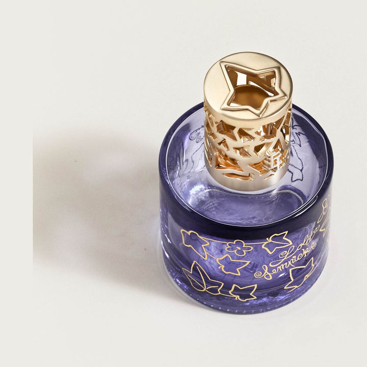 Top-down view of the Lampe Berger Lolita Lempicka violet-blue glass lamp, showing the cylindrical bottle, gold ivy decoration and satin-gold diffuser cap with an ivy-shaped opening.
