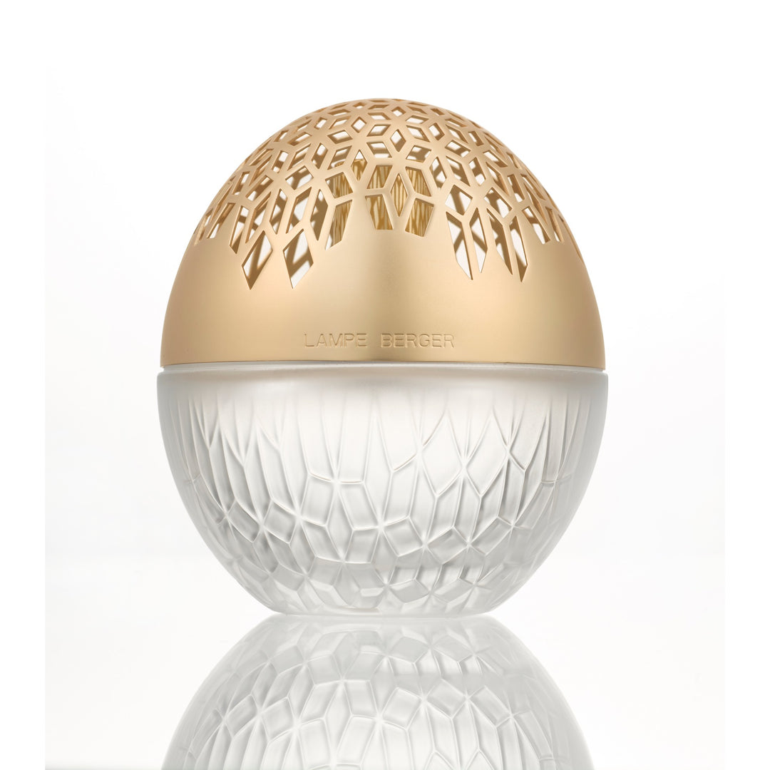 Lampe Berger Luka Oval Frosted home fragrance lamp in frosted white patterned glass with a warm gold-toned domed top with geometric cut-outs, reflected on the surface below.
