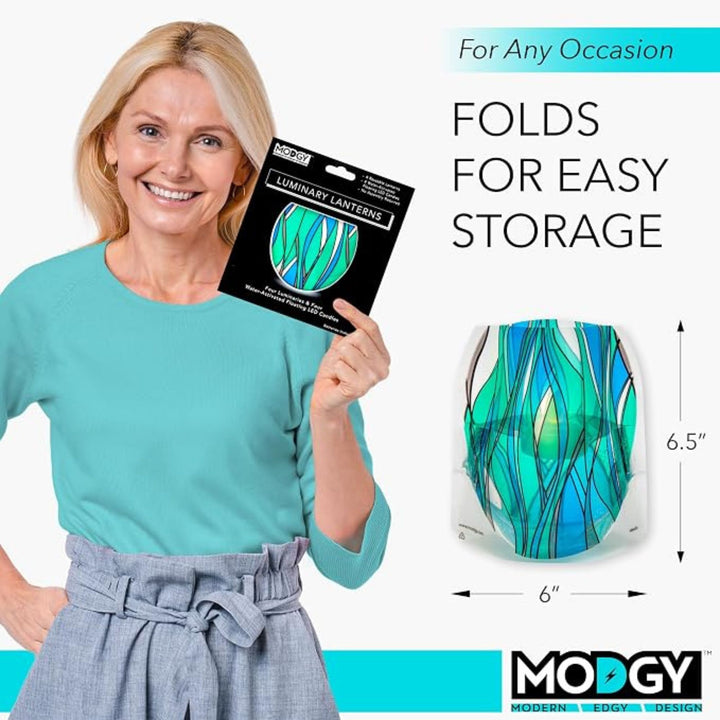 Modgy Heedo LED luminary package held for scale, showing the reusable lantern expands to approximately 6" × 6.5"