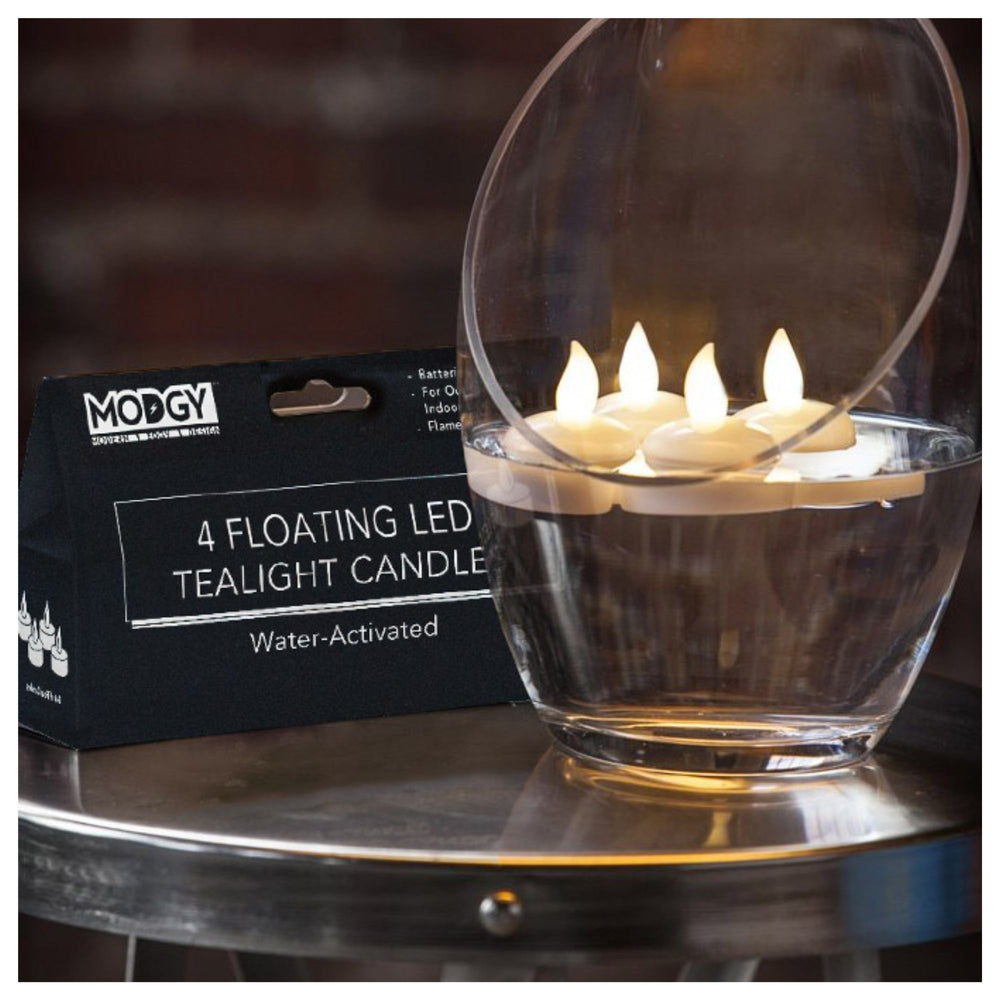 4 illuminated Modgy water-activated floating LED candles floating in water, illustrating the warm ambient glow.