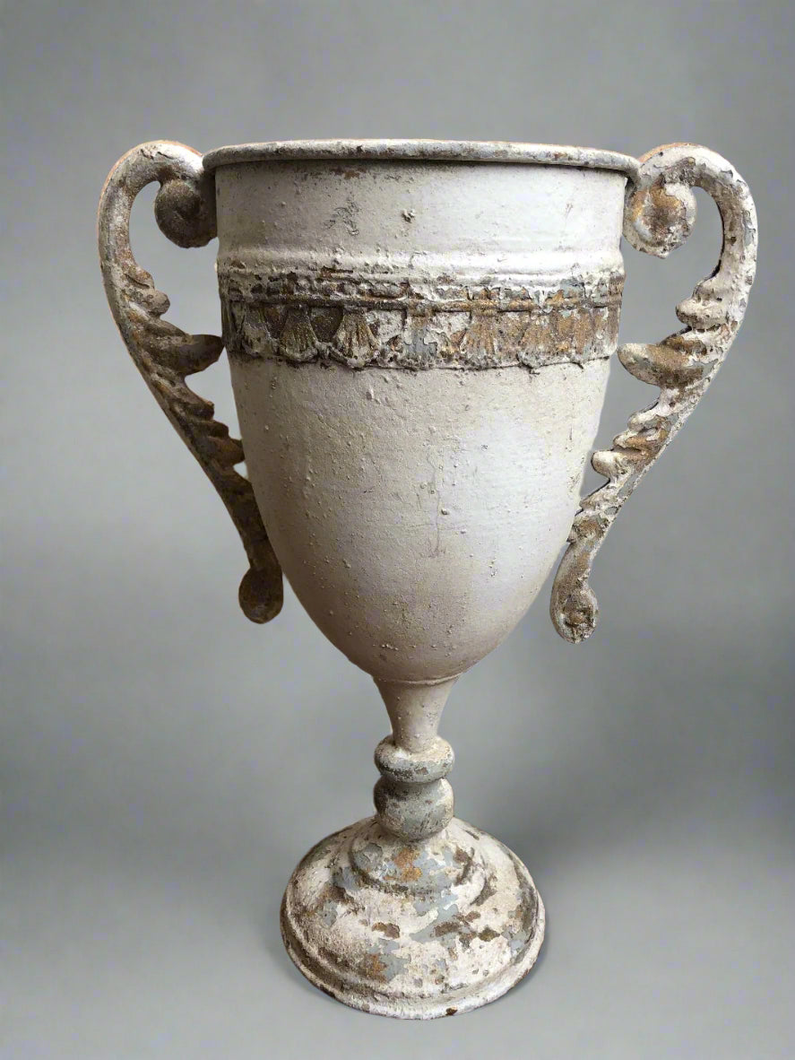 A white antiqued decorative urn with detailed handles and a round base, showing signs of wear and age.